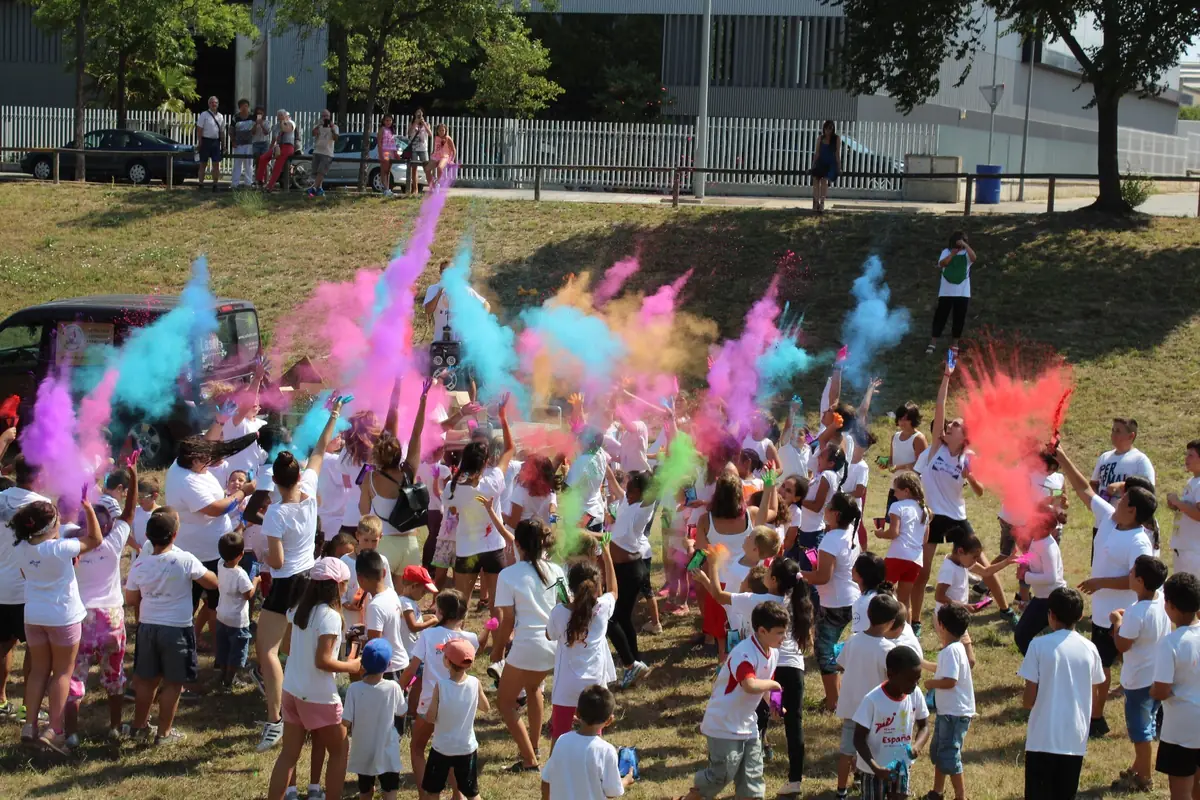Una plaça plena d'infants coberts de pols de colors durant una festa Holi