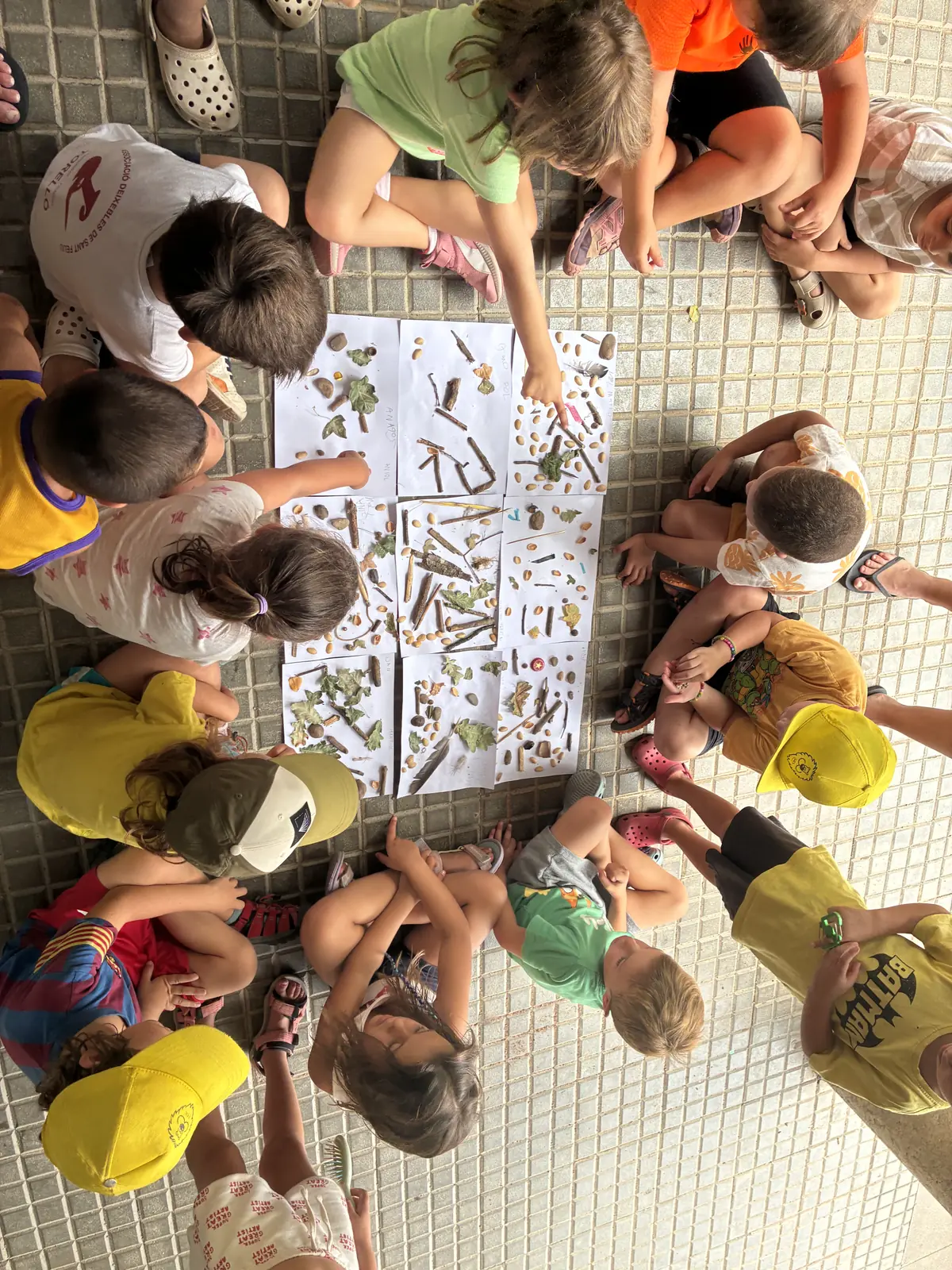 Infants jugant a un joc de taula gegant a terra, vistos des de dalt