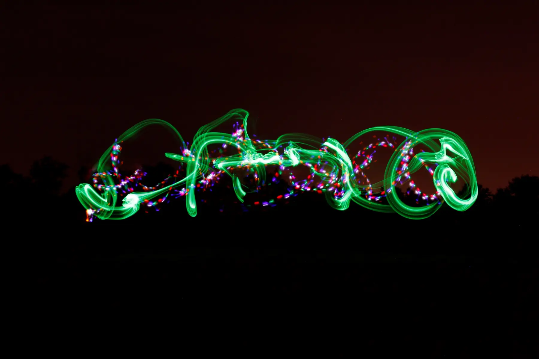 Traços de llum verds i roses dibuixats a la fosca en una sessió de lightpainting